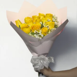 Ramo de 12 rosas amarillas con follaje envueltas en papel coreano coreano con moño rojo.