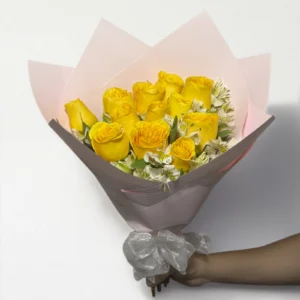 Ramo de 12 rosas amarillas con follaje envueltas en papel coreano coreano con moño rojo.