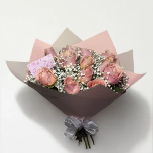 Ramo de 12 rosas rosas con follaje envueltas en papel coreano coreano con moño rojo.