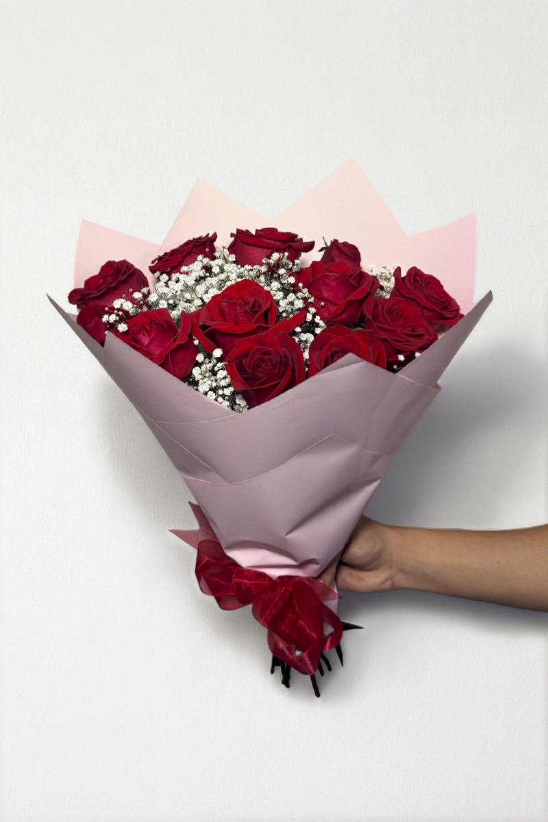 Ramo de 12 rosas rojas con follaje envueltas en papel coreano coreano con moño rojo.