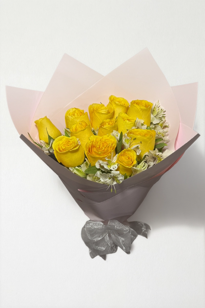 Ramo de 12 rosas amarillas con follaje envueltas en papel coreano coreano con moño rojo.