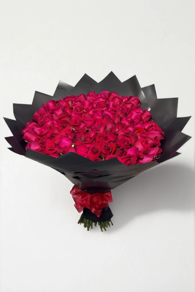 Ramo de 100 rosas rojas con follaje envueltas en papel coreano con moño.