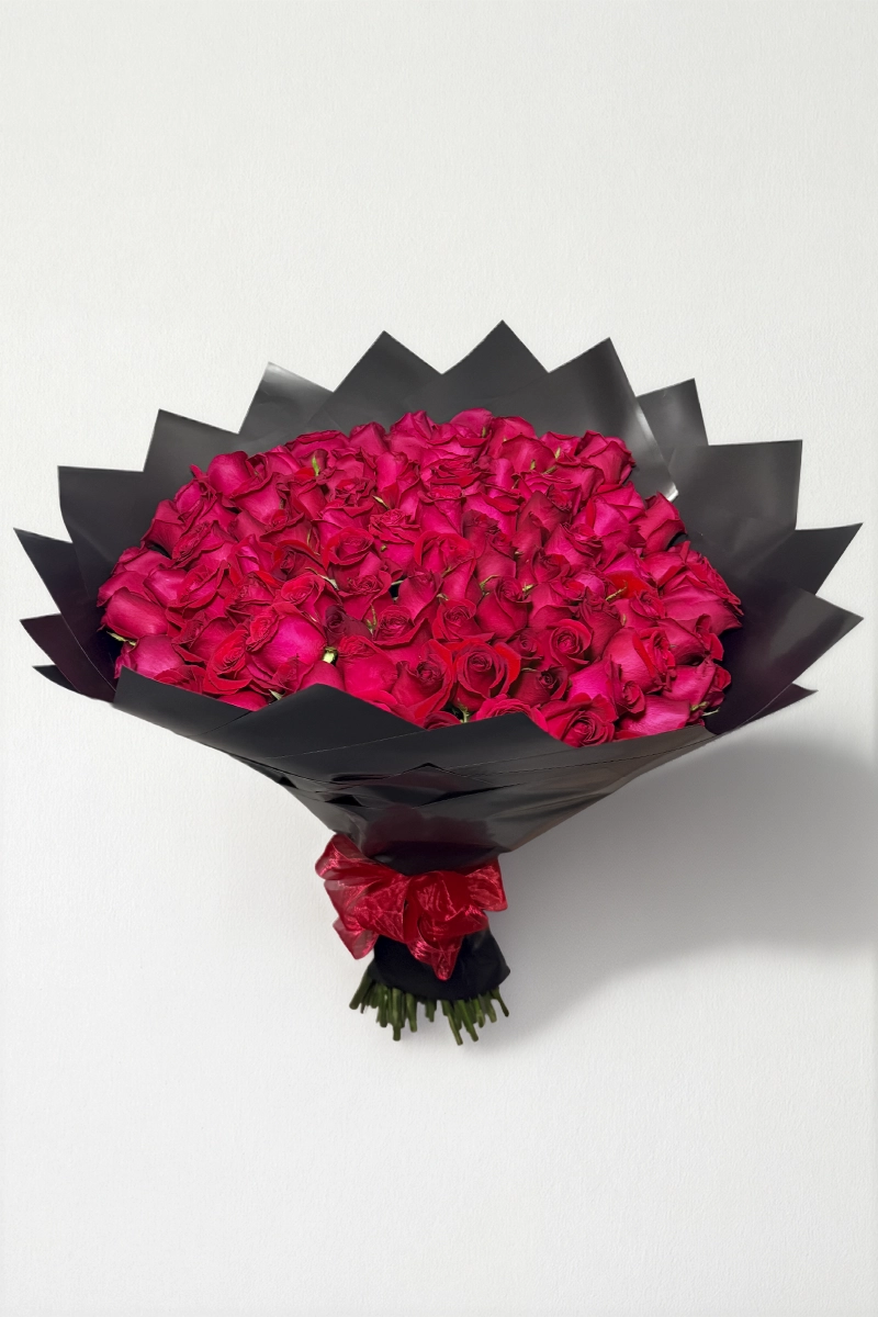 Ramo de 100 rosas rojas con follaje envueltas en papel coreano con moño.
