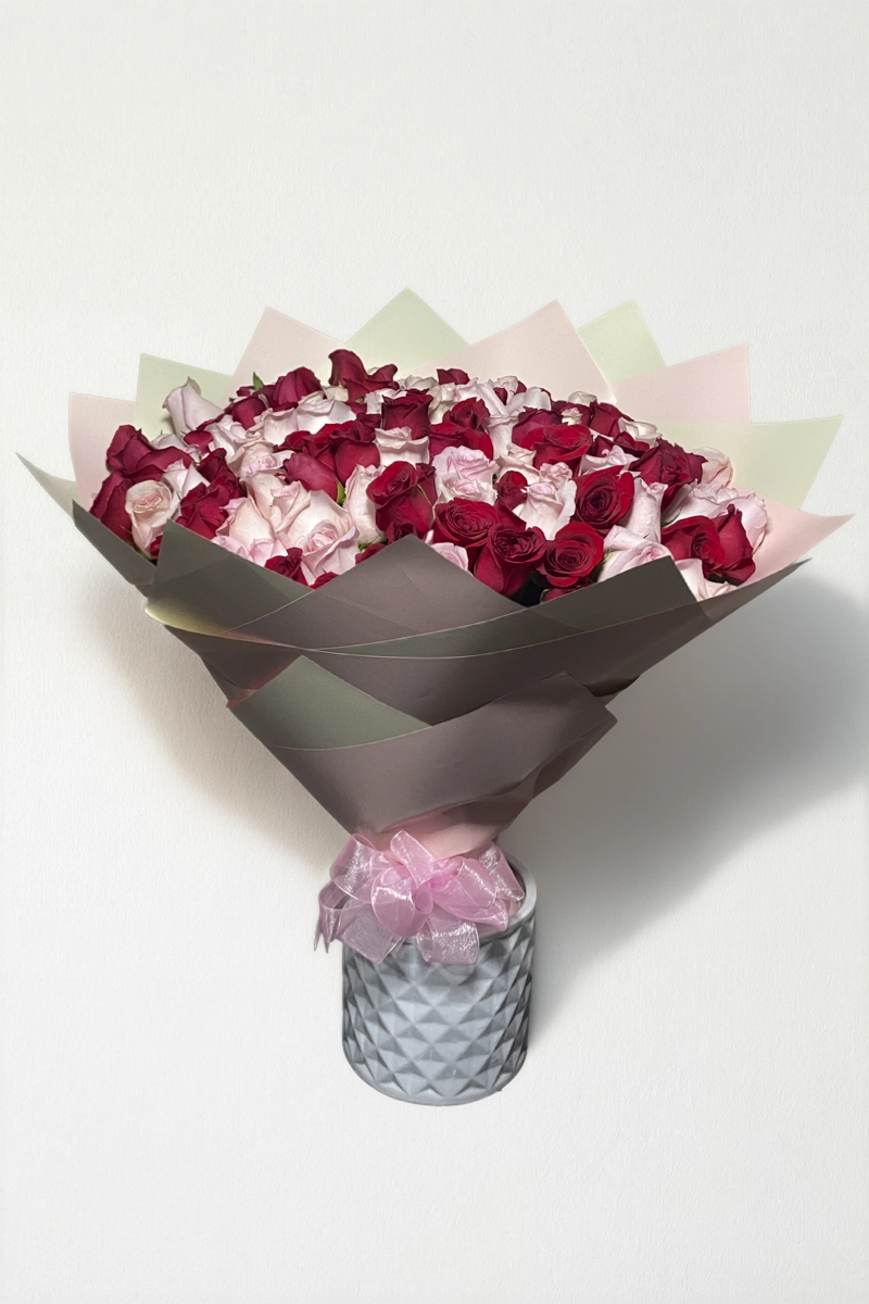 Ramo de 100 rosas rojas y rosas con follaje envueltas en papel coreano con moño.