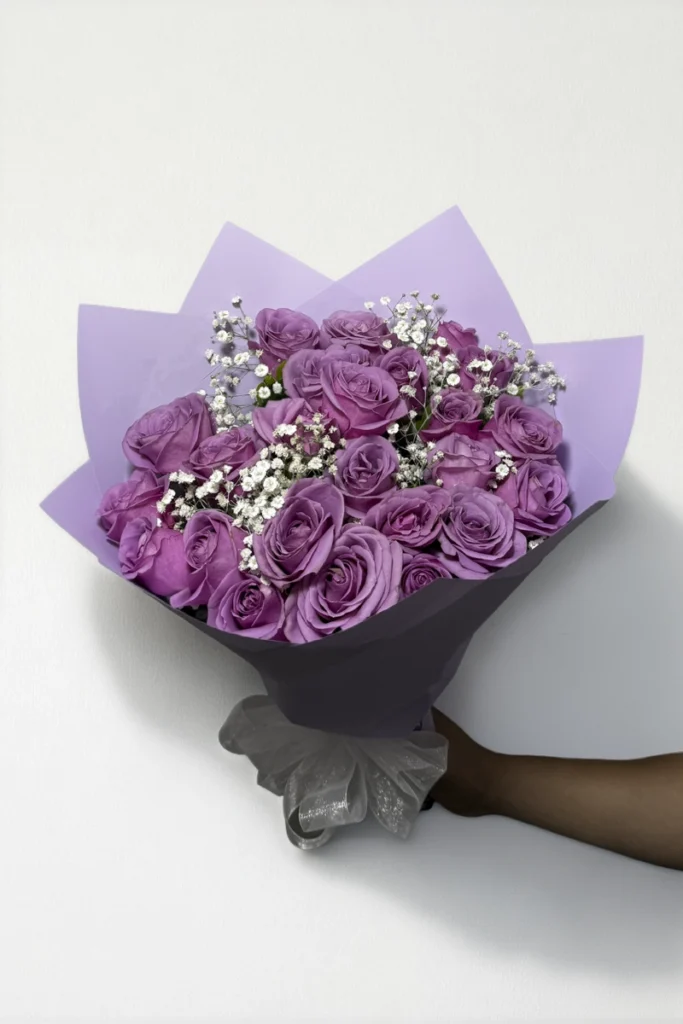 Ramo de 24 rosas lila con follaje envueltas en papel coreano con moño.