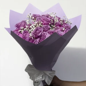 Ramo de 24 rosas lila con follaje envueltas en papel coreano con moño.
