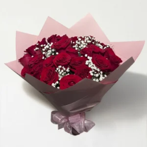 Ramo de 24 rosas rojo con follaje envueltas en papel coreano con moño.
