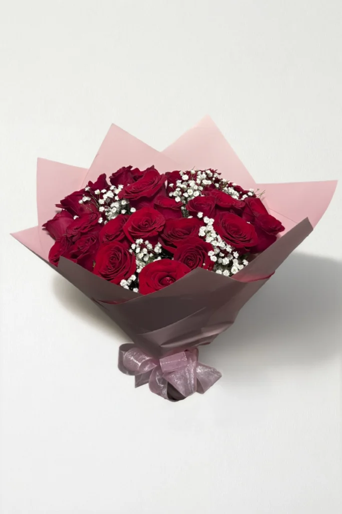 Ramo de 24 rosas rojo con follaje envueltas en papel coreano con moño.