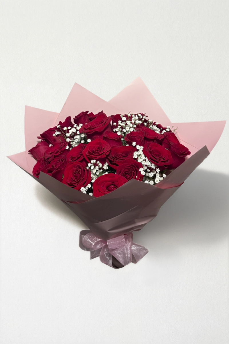 Ramo de 24 rosas rojo con follaje envueltas en papel coreano con moño.