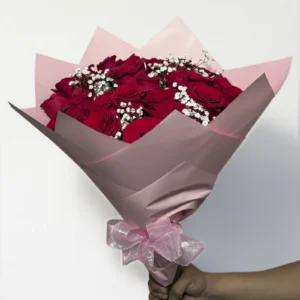 Ramo de 24 rosas rojas con follaje envueltas en papel coreano con moño.