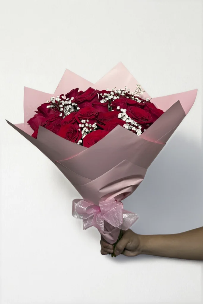 Ramo de 24 rosas rojas con follaje envueltas en papel coreano con moño.