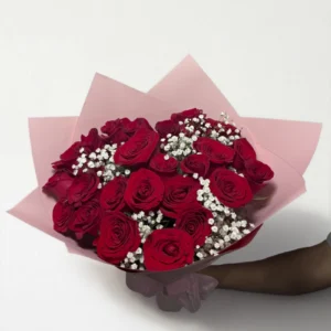 Ramo de 24 rosas rojas con follaje envueltas en papel coreano con moño.