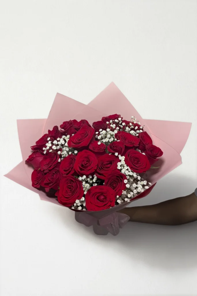 Ramo de 24 rosas rojas con follaje envueltas en papel coreano con moño.