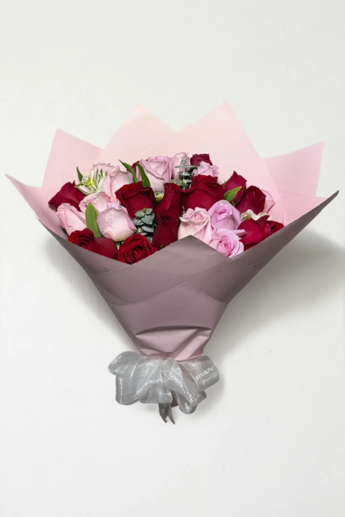 Ramo de 24 rosas rojas y rosas con follaje envueltas en papel coreano con moño.