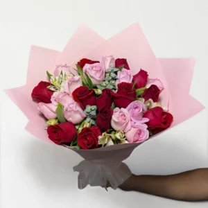 Ramo de 24 rosas rojas y rosas con follaje envueltas en papel coreano con moño.