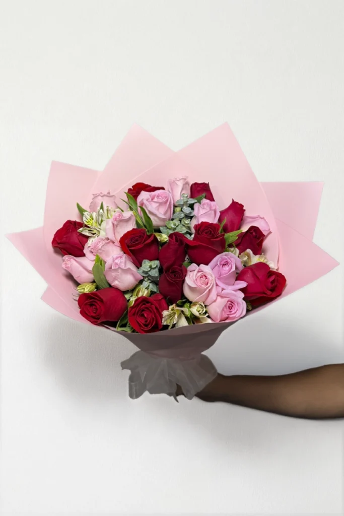 Ramo de 24 rosas rojas y rosas con follaje envueltas en papel coreano con moño.