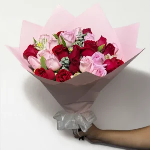 Ramo de 24 rosas rojas y rosas con follaje envueltas en papel coreano con moño.