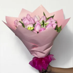 Ramo de 24 rosas rosas con follaje envueltas en papel coreano con moño.