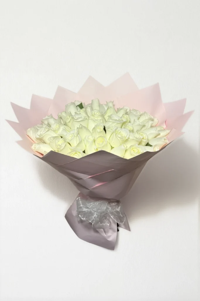 Ramo de 50 rosas blancas con follaje envueltas en papel coreano con moño.