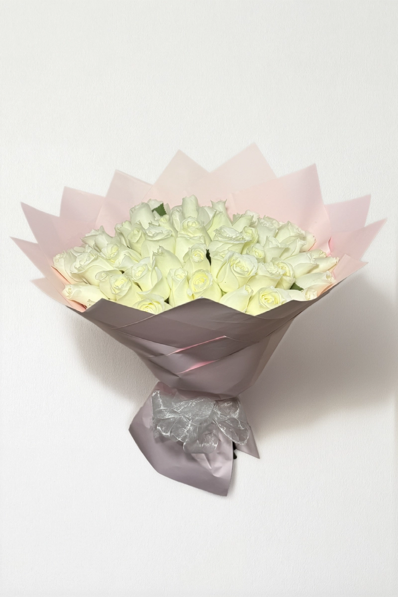 Ramo de 50 rosas blancas con follaje envueltas en papel coreano con moño.
