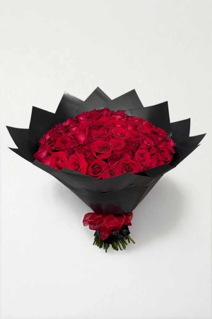 Ramo de 50 rosas rojas con follaje envueltas en papel coreano con moño.