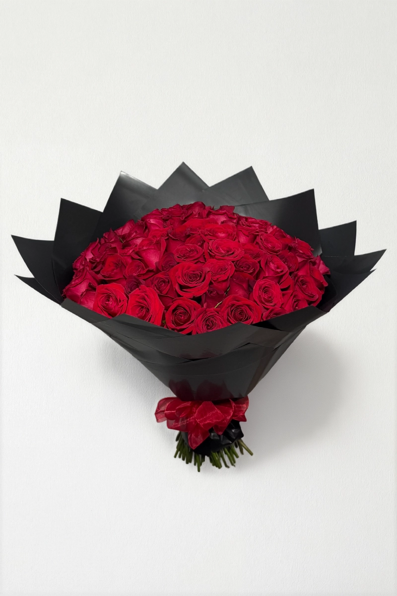 Ramo de 50 rosas rojas con follaje envueltas en papel coreano con moño.